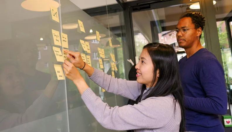Deux personnes réfléchissent à l'aide de post-its.